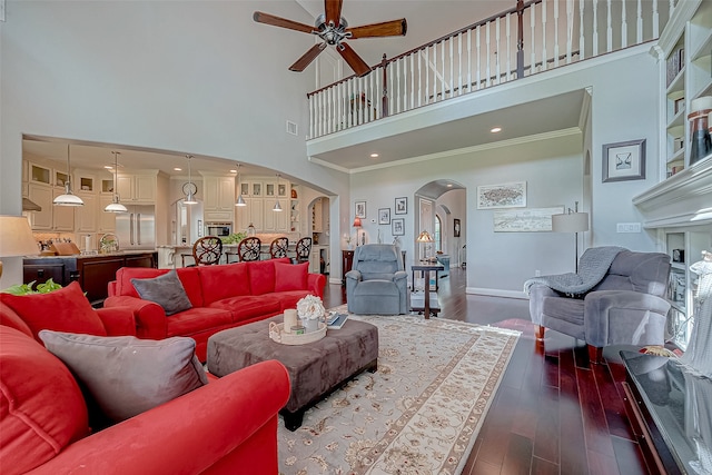 living room featuring dark hardwood / wood-style flooring, a towering ceiling, ceiling fan, and crown molding