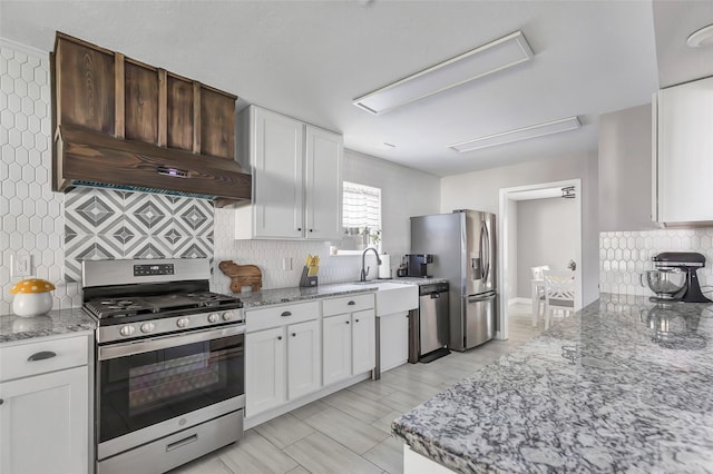 kitchen featuring backsplash, white cabinets, custom range hood, and appliances with stainless steel finishes