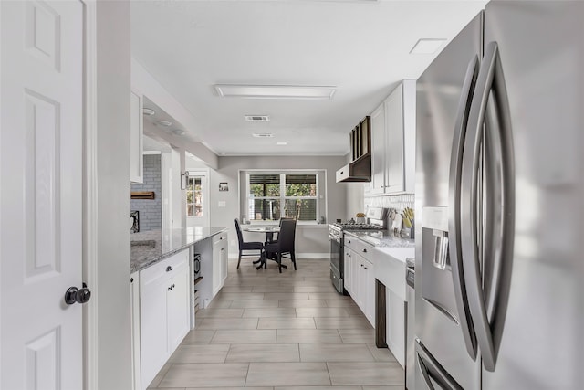 kitchen with white cabinets, backsplash, light stone counters, and stainless steel appliances