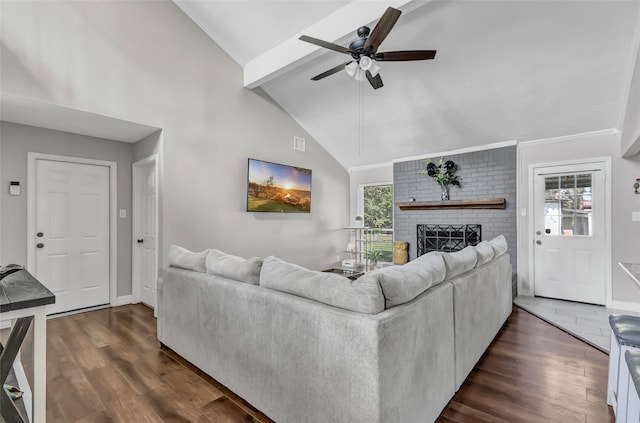 living room with vaulted ceiling with beams, dark hardwood / wood-style floors, a brick fireplace, and ceiling fan