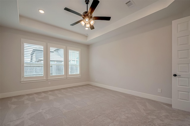 unfurnished room with light carpet, a tray ceiling, and ceiling fan