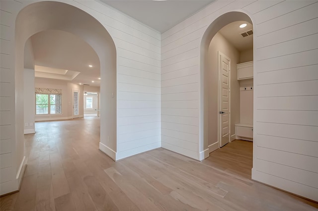 hallway featuring light hardwood / wood-style floors and wooden walls