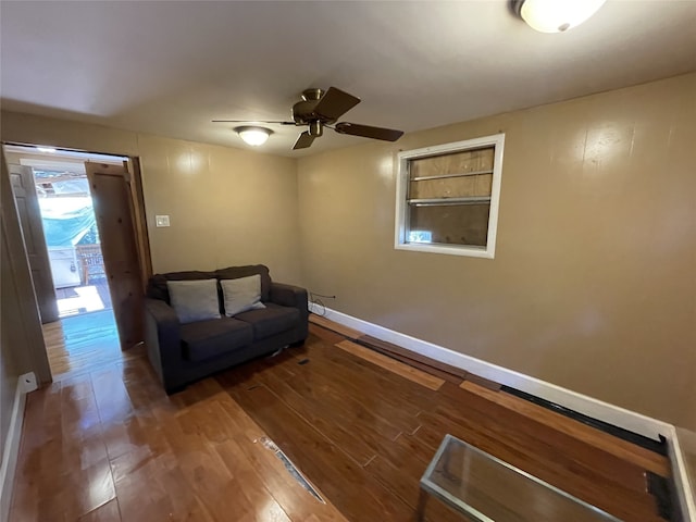 living area with ceiling fan and dark wood-type flooring