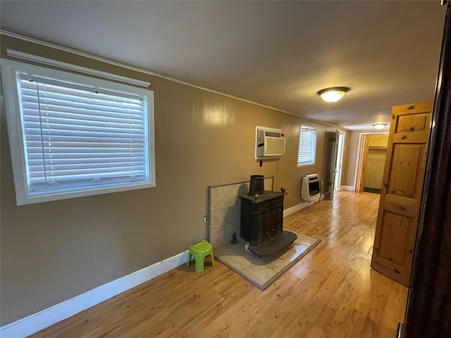 living room featuring heating unit, a healthy amount of sunlight, a wood stove, and light hardwood / wood-style flooring