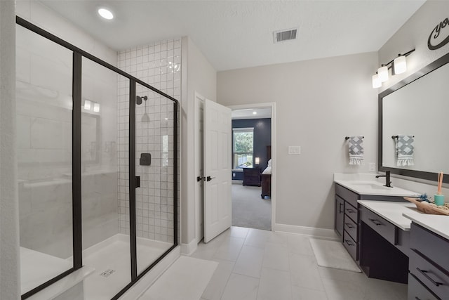 bathroom with tile patterned flooring, a textured ceiling, vanity, and walk in shower