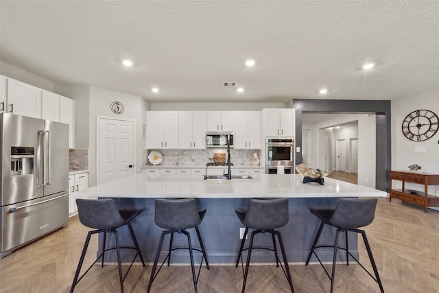 kitchen with white cabinets, appliances with stainless steel finishes, a breakfast bar, and a spacious island