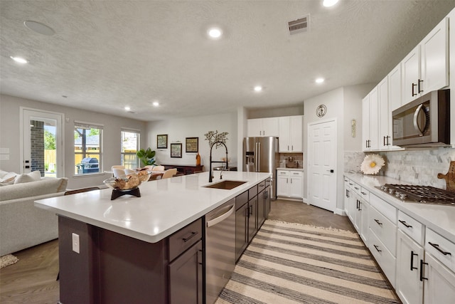 kitchen with white cabinets, a kitchen island with sink, sink, and appliances with stainless steel finishes