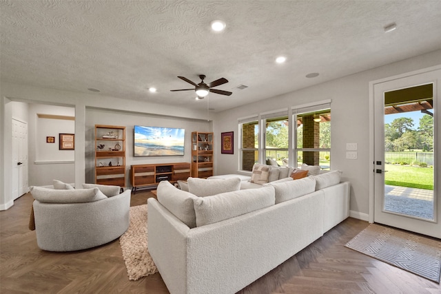 living room featuring a textured ceiling, ceiling fan, and dark parquet floors