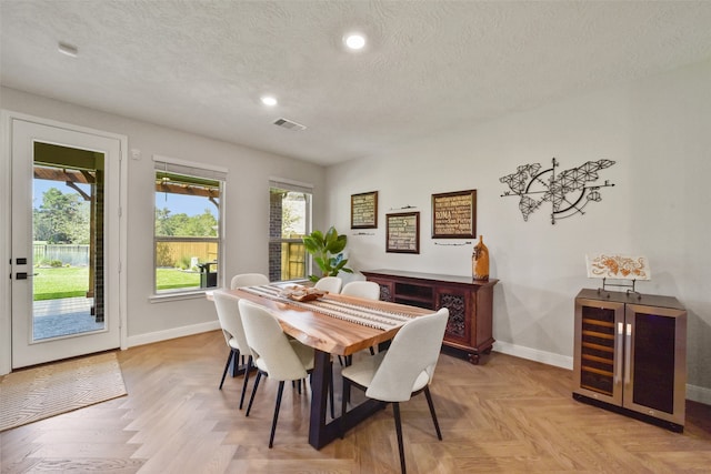 dining area with a textured ceiling, light parquet floors, and plenty of natural light