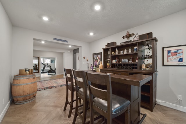 bar with light parquet flooring and a textured ceiling