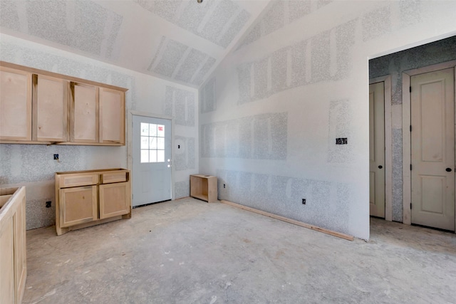 kitchen featuring light brown cabinetry and lofted ceiling