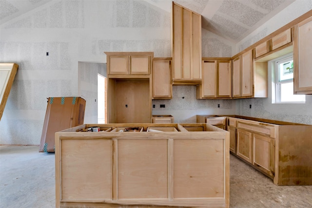 kitchen featuring light brown cabinetry and vaulted ceiling