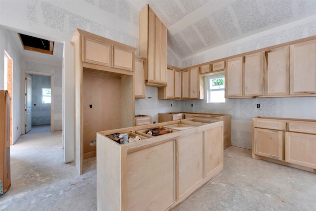 kitchen with a center island, light brown cabinets, and lofted ceiling