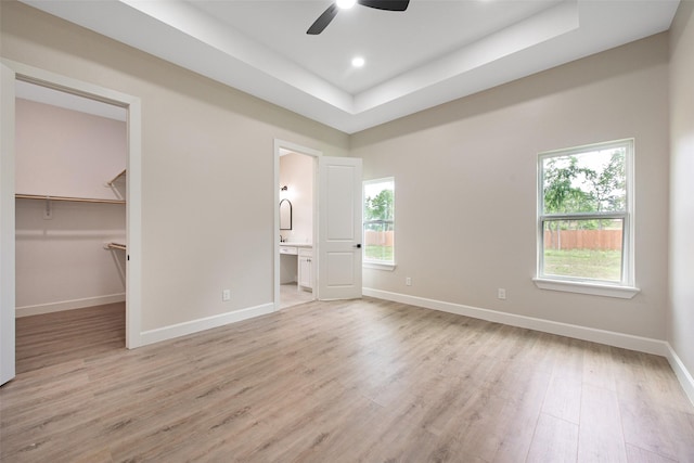24601 Tipperary St, Hempstead, TX 77445 - unfurnished bedroom with light wood-style floors, baseboards, a tray ceiling, a spacious closet, and ensuite bath