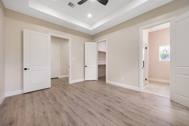 24601 Tipperary St, Hempstead, TX 77445 - unfurnished bedroom featuring visible vents, a raised ceiling, baseboards, a spacious closet, and light wood-style flooring
