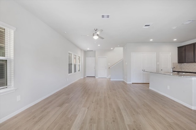 unfurnished living room with light wood-type flooring, ceiling fan, and sink