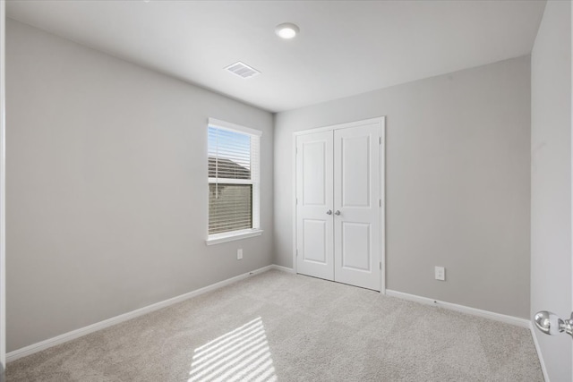 unfurnished bedroom featuring light colored carpet and a closet