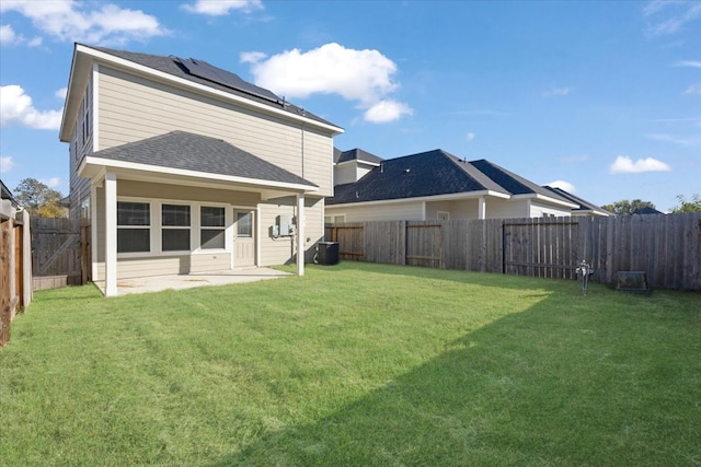 back of house with solar panels, cooling unit, a patio area, and a lawn