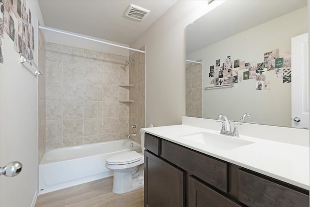 full bathroom featuring vanity, hardwood / wood-style floors, tiled shower / bath combo, and toilet