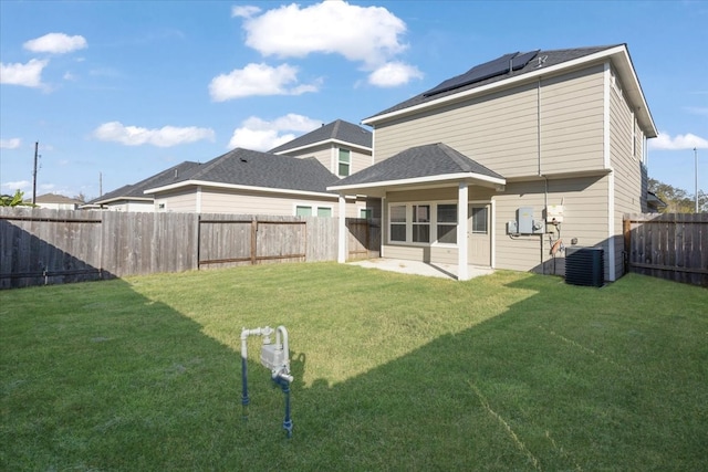 rear view of property featuring solar panels, central air condition unit, a patio area, and a lawn