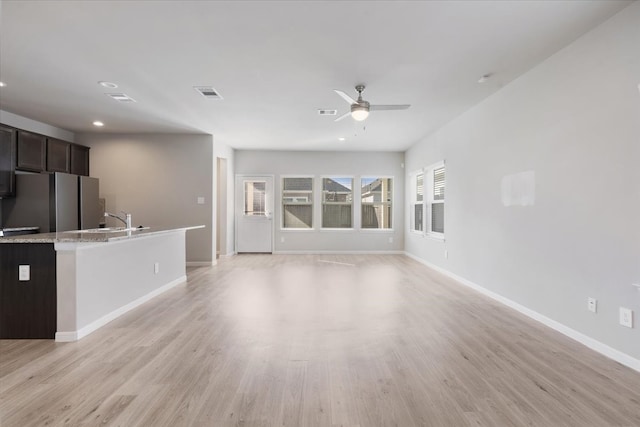 unfurnished living room featuring light hardwood / wood-style flooring, ceiling fan, and sink