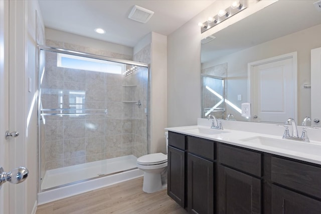 bathroom featuring vanity, wood-type flooring, a shower with shower door, and toilet