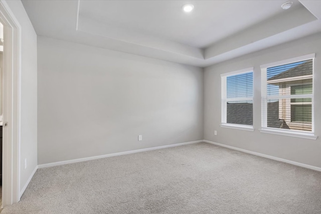 carpeted empty room featuring a raised ceiling