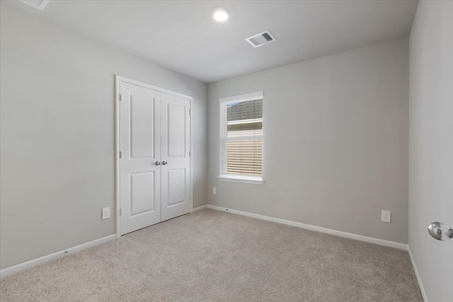 unfurnished bedroom featuring light colored carpet and a closet