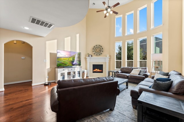 living room featuring ceiling fan, a towering ceiling, and dark wood-type flooring