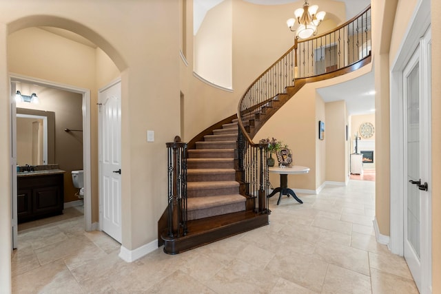 entryway with baseboards, stairway, a high ceiling, an inviting chandelier, and arched walkways