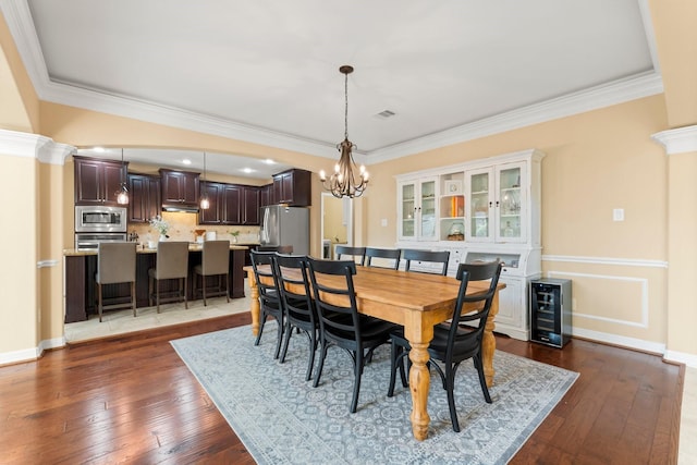 dining space featuring ornamental molding, hardwood / wood-style floors, wine cooler, an inviting chandelier, and baseboards