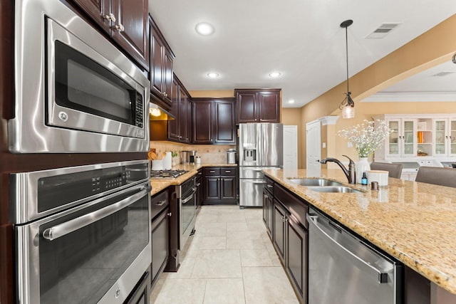 kitchen featuring dark brown cabinetry, sink, stainless steel appliances, pendant lighting, and ornamental molding