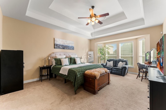 bedroom with a tray ceiling, light colored carpet, and baseboards