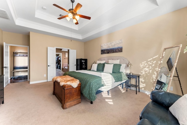 carpeted bedroom with ceiling fan and a tray ceiling