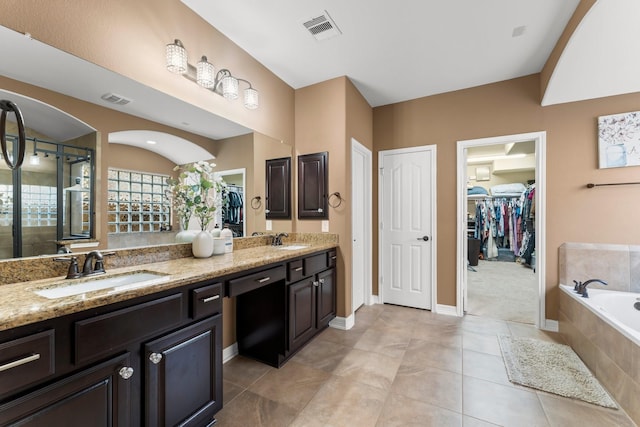 bathroom featuring vanity, tile patterned floors, and tiled tub