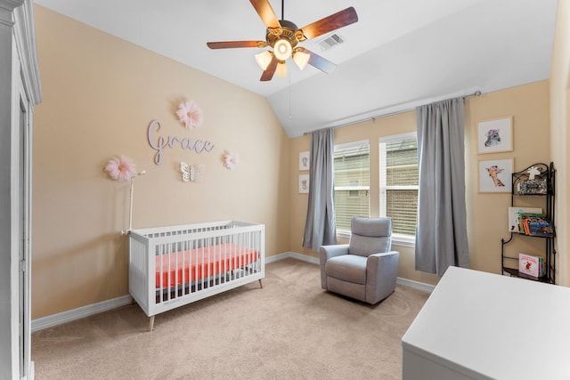 bedroom featuring lofted ceiling, ceiling fan, light carpet, and a crib