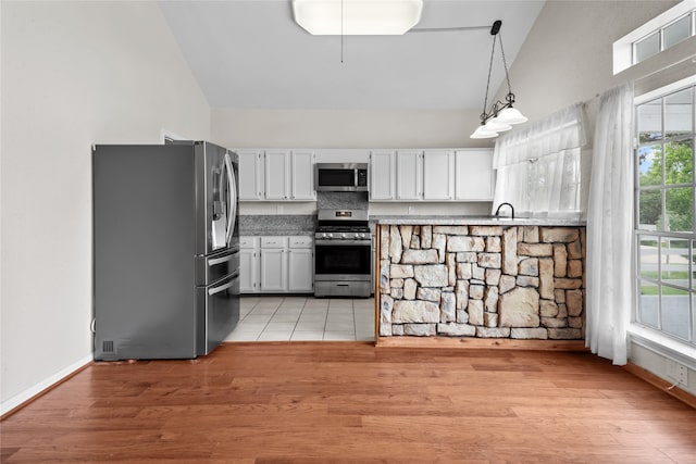 kitchen with white cabinetry, hanging light fixtures, high vaulted ceiling, and appliances with stainless steel finishes