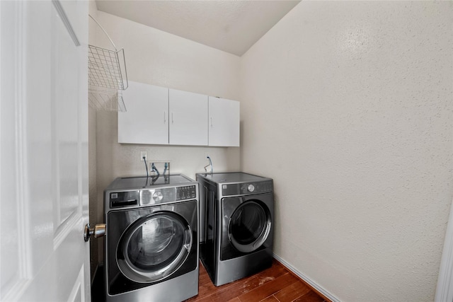 washroom with dark wood-type flooring, cabinets, and washer and clothes dryer