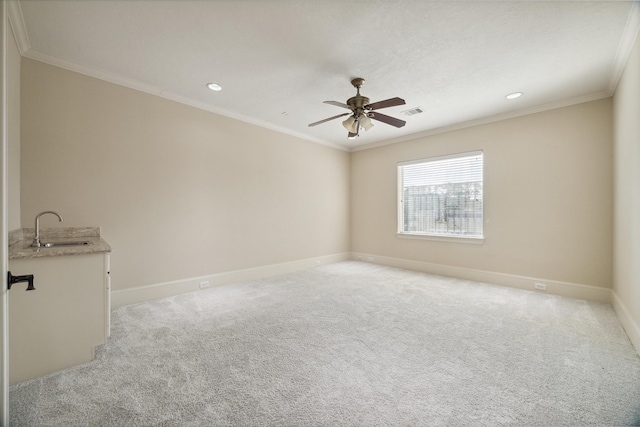 unfurnished room featuring ceiling fan, crown molding, sink, and light carpet