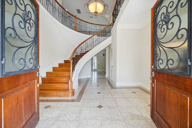 tiled entryway with crown molding and a high ceiling