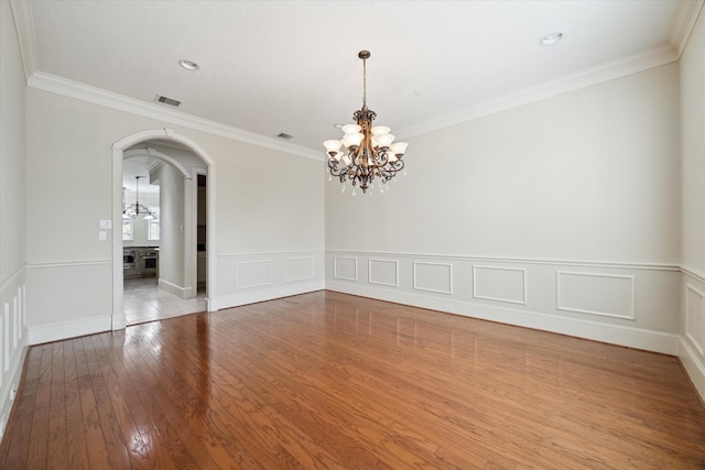 spare room featuring an inviting chandelier, light hardwood / wood-style flooring, and crown molding