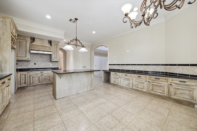 kitchen featuring premium range hood, pendant lighting, a breakfast bar, a kitchen island, and ornamental molding