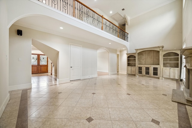 unfurnished living room with light tile patterned floors, ornamental molding, a high ceiling, and french doors