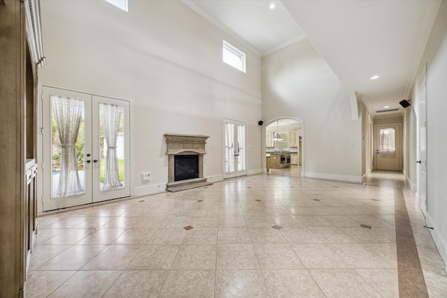 unfurnished living room featuring french doors, light tile patterned floors, crown molding, and a high ceiling