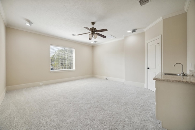 carpeted empty room with a textured ceiling, ceiling fan, crown molding, and sink