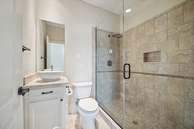 bathroom featuring vanity, toilet, and a shower with shower door