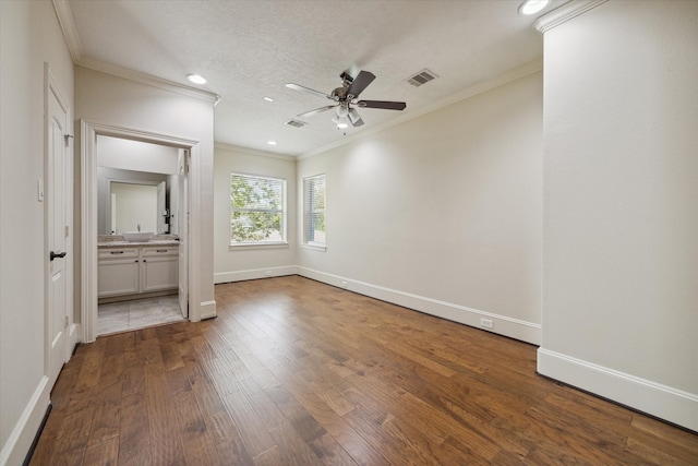 unfurnished bedroom with ensuite bath, ceiling fan, dark wood-type flooring, and ornamental molding