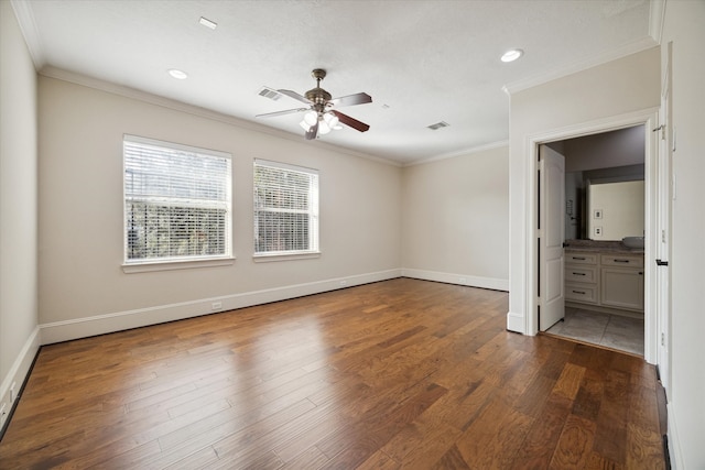 unfurnished bedroom featuring ceiling fan, crown molding, dark wood-type flooring, and connected bathroom