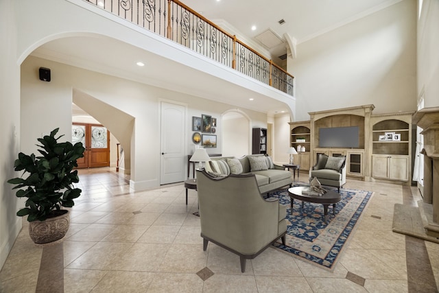 tiled living room with built in features, ornamental molding, and a high ceiling