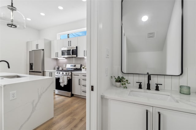 kitchen featuring white cabinets, sink, appliances with stainless steel finishes, and light hardwood / wood-style flooring